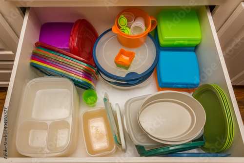 Kitchen drawer filled with colorful plastic storage containers photo