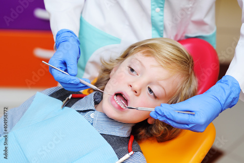 smiling child with light curly hair on examination in the dental chair