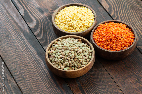 Uncooked raw red, yellow and green lentil in bowl on wooden background, (Lens culinaris)