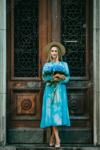 Summer portrait of a beautiful woman with flowers of hydragea in front of vintage doors