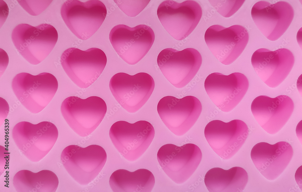 Silicone confectionery mold made of silicone in the form of small pink hearts close-up.