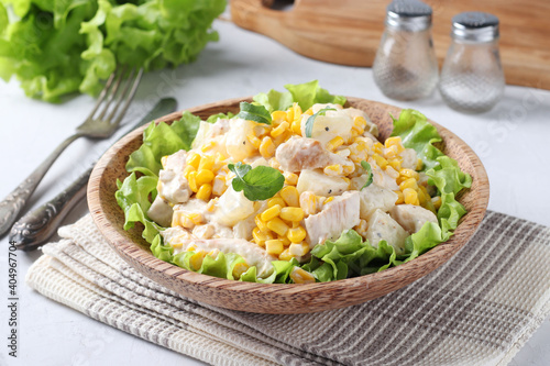 Salad with pineapple, baked chicken and corn on a plate of coconut, Closeup. Horizontal format photo