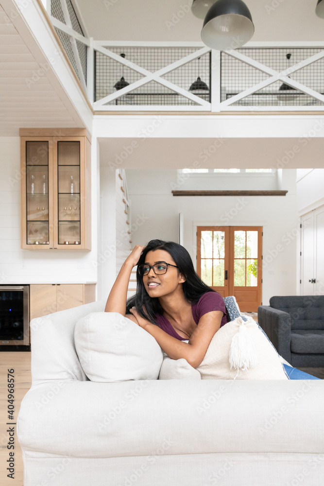 Happy Indian woman sitting on the couch in a modern farmhouse-style ...