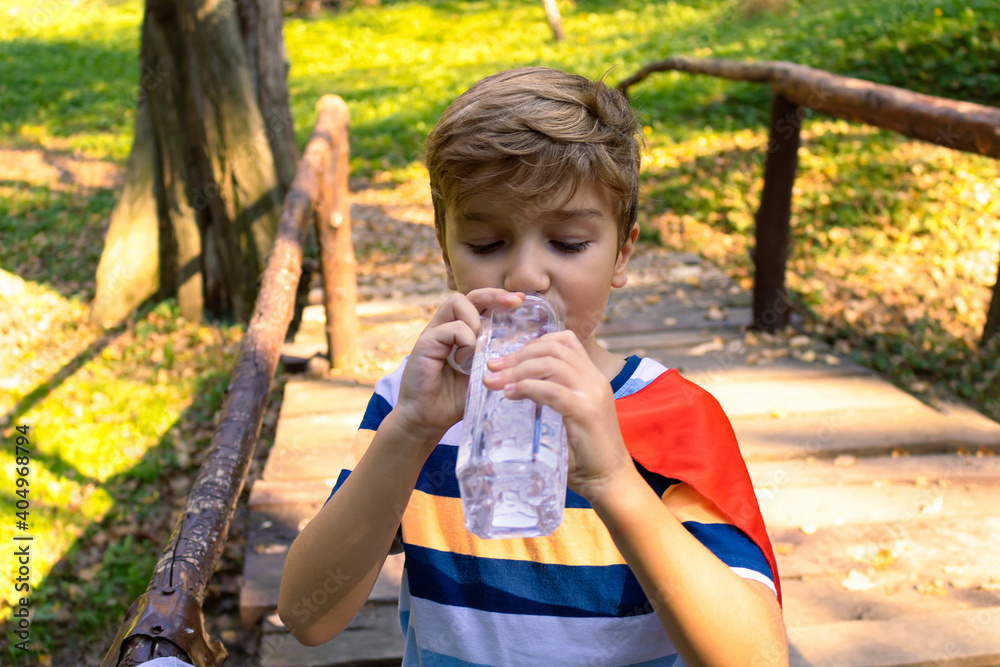 Thirsty boy drinking water from a bottle in nature. Thirsty boy drinking water from a bottle in nature.