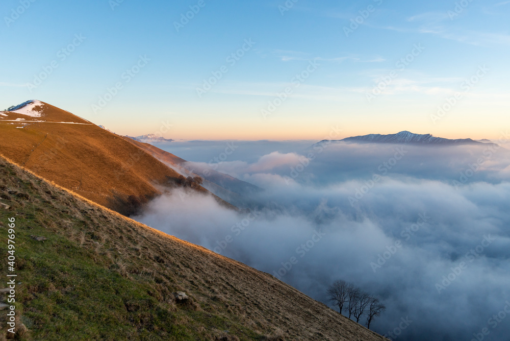 Mountains emerging from a sea of clouds. Atomspheric winter scenery in the Italian prealps