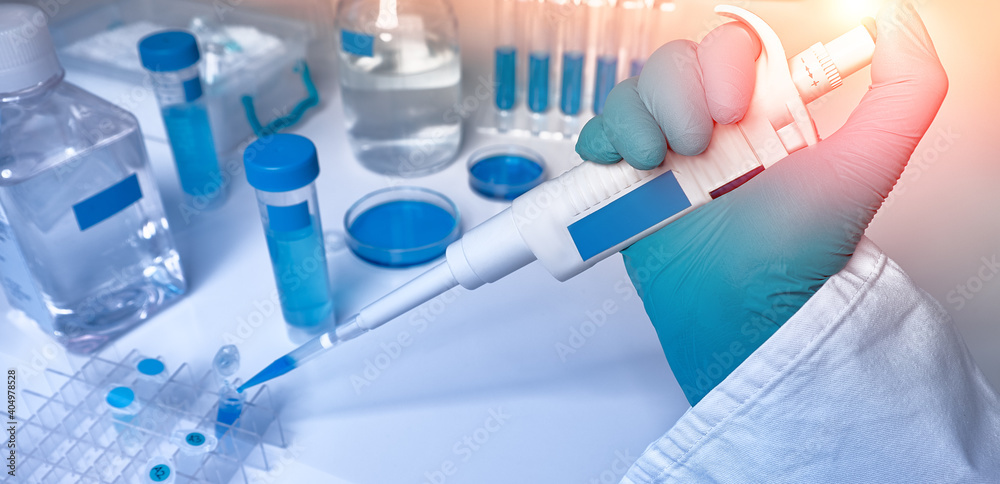 Hand in glove with automatic pipette and samples, panoramic image. Polymerase Chain Reaction PCR used in medical testing, biochemistry, molecular biology, genetics, clinical research in lab. Hand in glove with automatic pipette and samples, panoramic image. Polymerase Chain Reaction PCR used in medical testing, biochemistry, molecular biology, genetics, clinical research in lab.