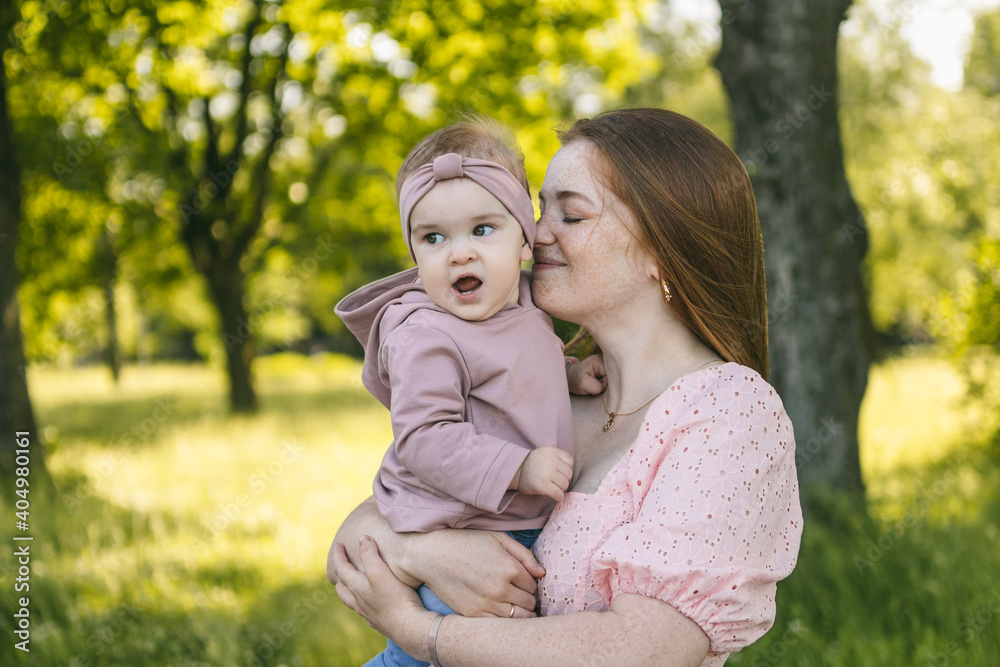 A young mother walks with a one-year-old baby, holds him in her arms, hugs. Communication with the child for his harmonious development A young mother walks with a one-year-old baby, holds him in her arms, hugs. Communication with the child for his harmonious development