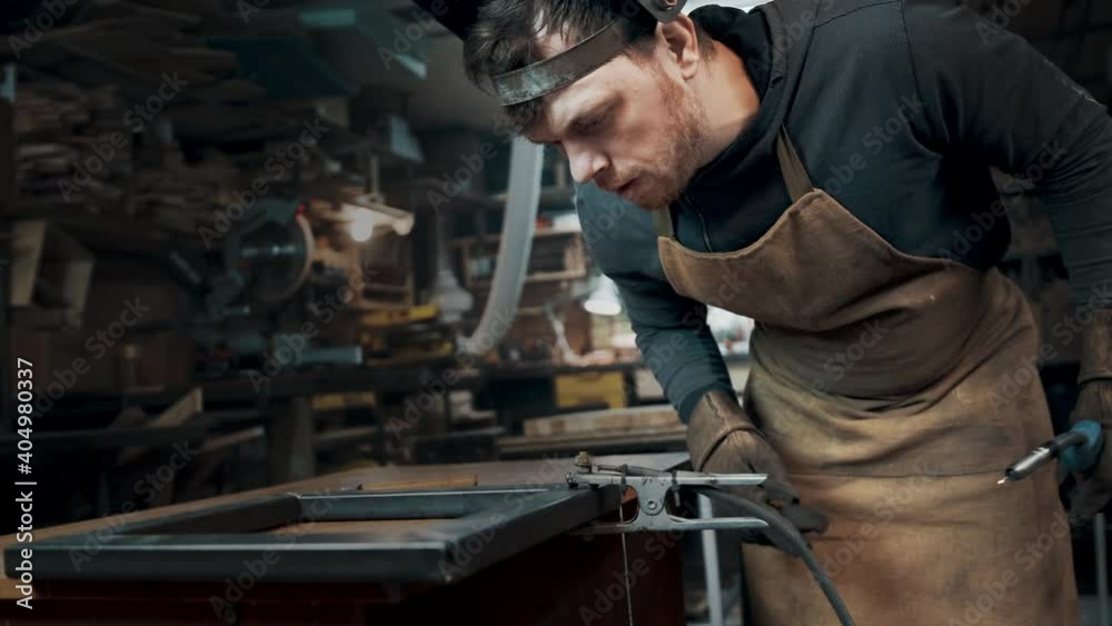 Worker wearing a mask and gloves soldering metal parts Worker wearing a mask and gloves soldering metal parts