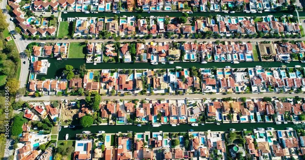 Flying above houses of a Surbubian community. Red roofs in idyllic suburban town with garden and waterway between houses - aerial view 4K Flying above houses of a Surbubian community. Red roofs in idyllic suburban town with garden and waterway between houses - aerial view 4K