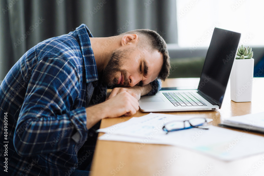 Tired freelancer man is fall asleep at the workplace. Exhausted busy guy working overtime, sits at the desk at home, need a rest, overwork concept. Work from home Tired freelancer man is fall asleep at the workplace. Exhausted busy guy working overtime, sits at the desk at home, need a rest, overwork concept. Work from home
