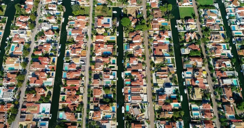 Flying above a suburban town in Spain. Red roofs in an idyllic and quiet Surbubian community with garden and waterway between houses 4K Flying above a suburban town in Spain. Red roofs in an idyllic and quiet Surbubian community with garden and waterway between houses 4K
