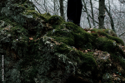 Fototapeta Naklejka Na Ścianę i Meble -  Plane of a hiker's feet and a moss-filled rock