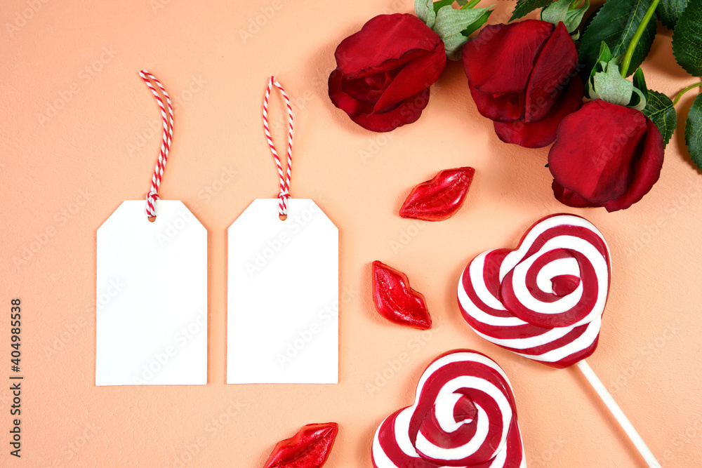 Φωτογραφία Happy Valentine's Day gift hang tag labels, styled with Valentine red roses, heart shape gift and lipstick kissess chocolates on a modern coral background