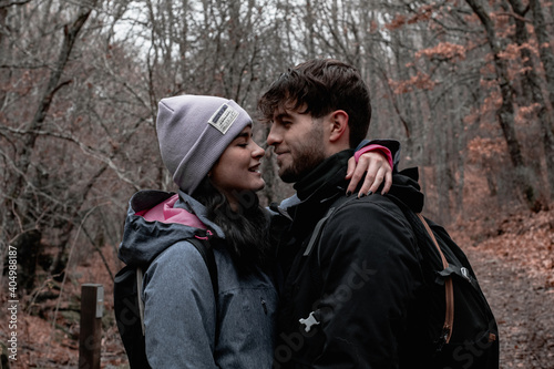 A young Caucasian couple looks at each other's eyes on the path of an autumn forest