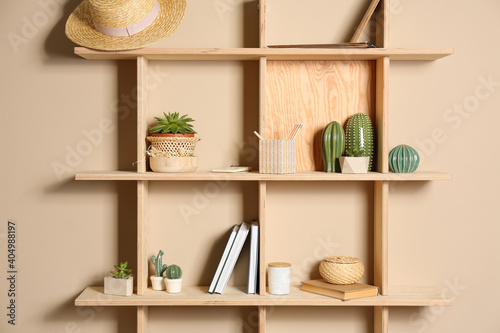 Wooden shelves with different decorative elements on beige wall © New Africa