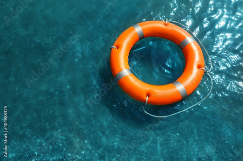 Orange life buoy floating in sea, above view. Emergency rescue equipment