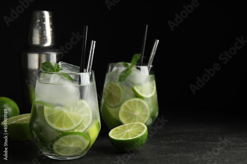 Delicious mojito and ingredients on black table
