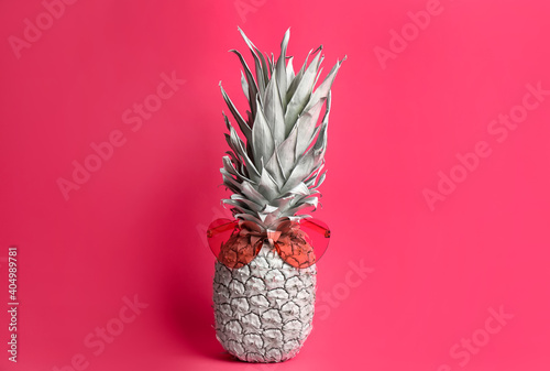 Painted pineapple with heart shaped sunglasses on pink background. Creative concept