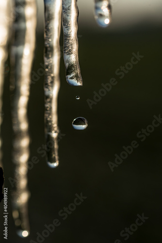 Melting icicles in the rays of the setting sun. The reflection of the horizon in falling water drops. Change in weather and temperature in winter.