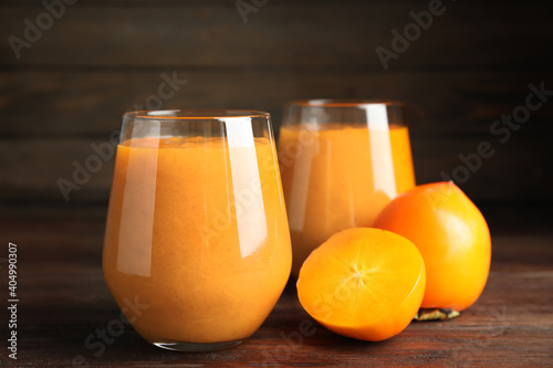 Tasty persimmon smoothie and fresh fruits on wooden table, closeup