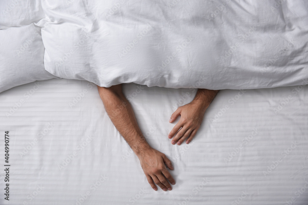 Man sleeping under soft blanket in bed at home, top view Man sleeping under soft blanket in bed at home, top view