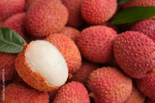 Pile of fresh ripe lychees with leaves as background, closeup