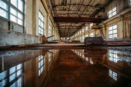 Inside of flooded dirty abandoned ruined industrial building with water reflection