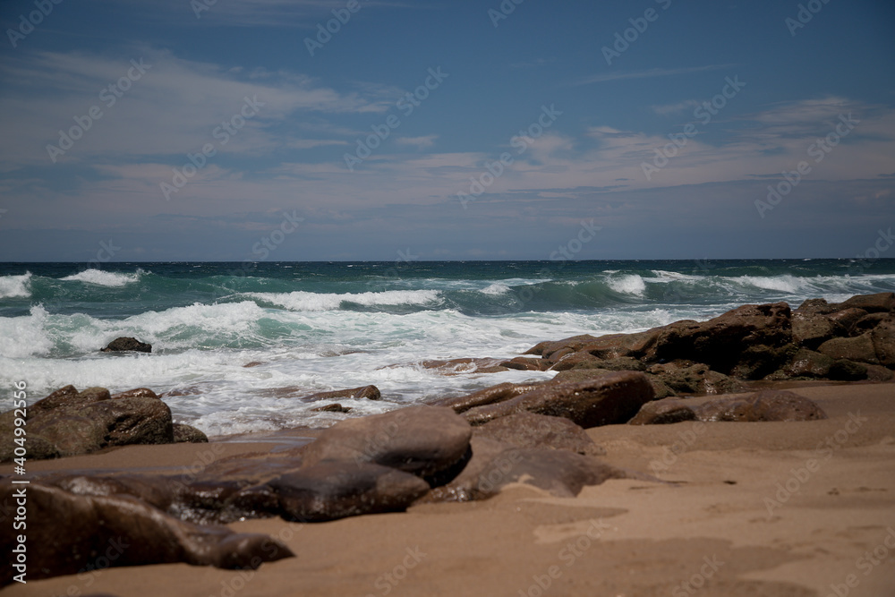 Beautiful sandy ocean beach with large rocks on the shore and in the water Beautiful sandy ocean beach with large rocks on the shore and in the water