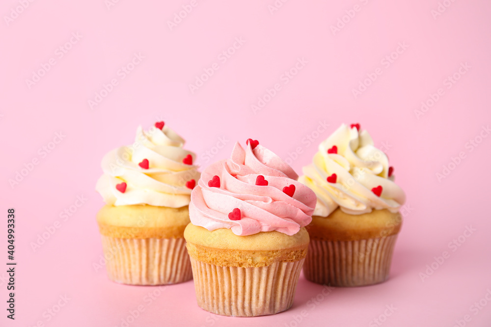 Tasty cupcakes with heart shaped sprinkles for Valentine's Day on pink background