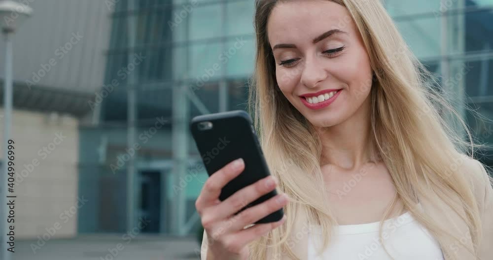 Pretty Young Woman standing in the City and looking at Frontal Camera of her Smartphone. Having lovely smile and Beautiful long Hair. Wearing formal clothes and having Charming Appearance. Pretty Young Woman standing in the City and looking at Frontal Camera of her Smartphone. Having lovely smile and Beautiful long Hair. Wearing formal clothes and having Charming Appearance.