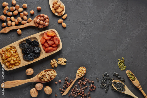 Different kinds of nuts, dried fruits on black slate background. Top view with copy space. Healthy food. Vegetarian nutrition