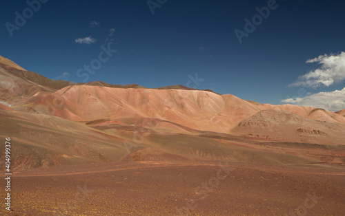 Desert landscape high in the Andes mountain range. View of the brown land, dunes and colorful mountains under a deep blue sky. 