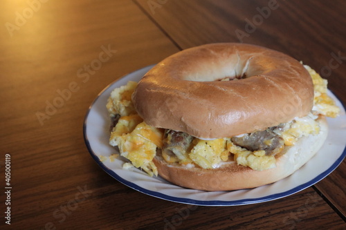 Big egg, sausage and cheese bagel breakfast sandwich on a wooden table photo