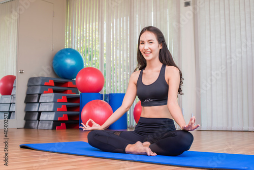Young asian woman doing yoga and background blur diverse equipment and fitness ball at the gym room. Fitness, sport, Advertise concept