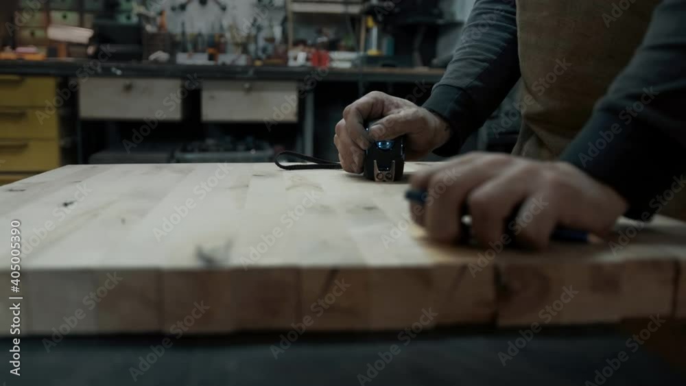 Carpenter's hands in an apron and a piece of wood Carpenter's hands in an apron and a piece of wood