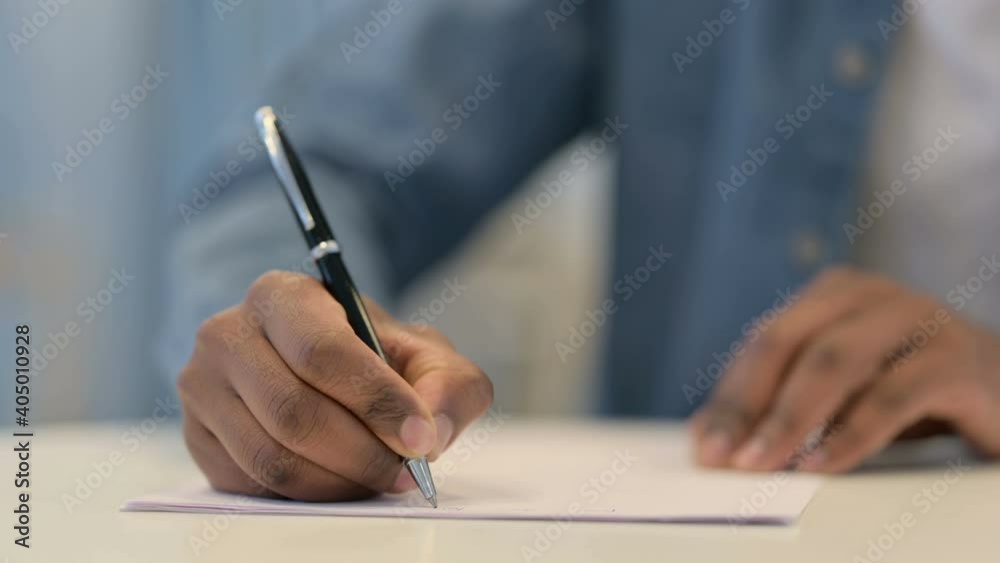 Hands of African Man Writing on Paper with Pen, Close Up