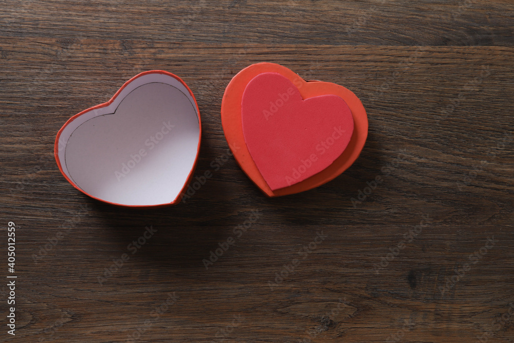 Red heart-shaped gift box on wooden background with space