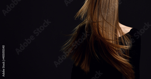 Portrait of woman shaking her head to makes her healthy strong long hair restored after spa procedures treatment flying over dark background with copy space . Hairstyle. Hair cosmetics photo