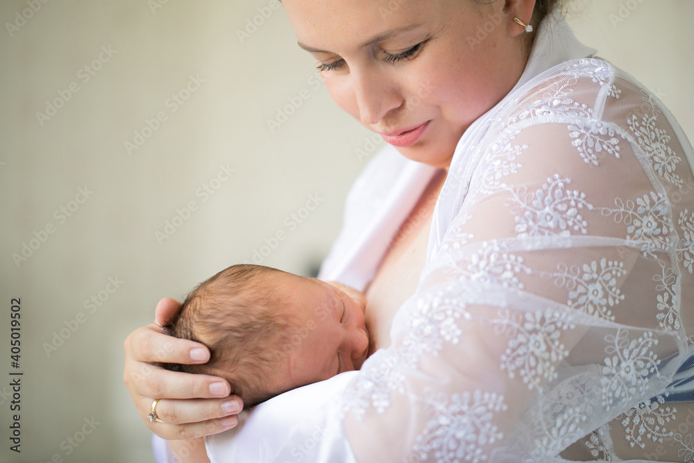 mom feeds newborn standing in a white interior. breastfeeding. Stock