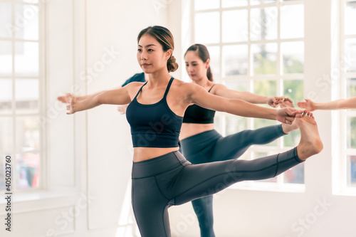 Group of Asian and Caucasian, male and female yoga together in indoor white studio with natural light. Concept of diversity, multi ethnic group of people and healthy lifestyle © Burin