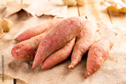 Raw sweet potato on wood background photo