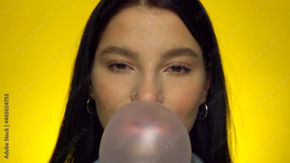 Attractive woman looking at camera, blowing bubble gum, smiling female portrait