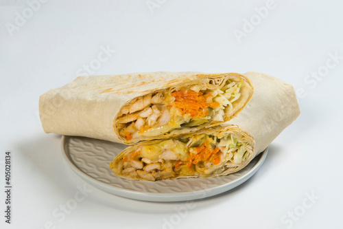 Side view of Two parts of Eastern cheesy shawarma with chicken meat, cucumber, cabbage, carrot, French fries served on plate, isolated on background. Turkish donner street food wrapped in lavash bread photo