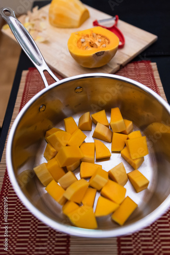pumpkin pieces in pot with pumpkin and peeler in background on cutting board