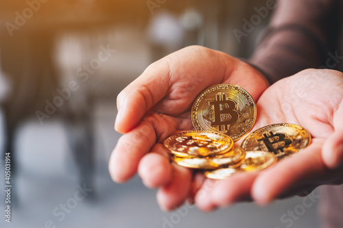Closeup image of a woman holding and showing golden color bitcoins in hands