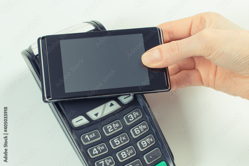 Hand using payment terminal and mobile phone with NFC technology. Cashless paying for different things Hand using payment terminal and mobile phone with NFC technology. Cashless paying for different things