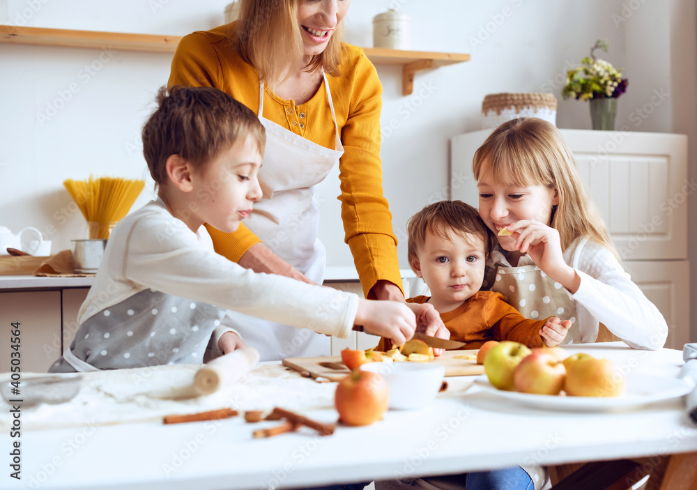 Three children preparing pie with loving caring mom on domestic kitchen
