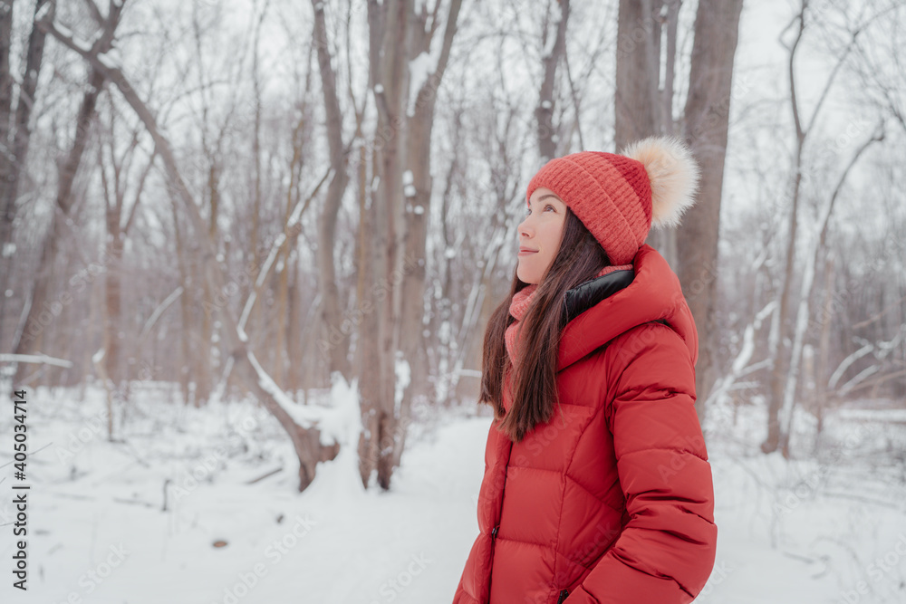 Asian woman happy outdoors in winter nature forest. Portrait of young multiracial ethnicity lady wearing red hat and coat.