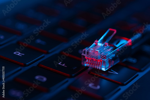 Close-up view of internet network cable on a laptop keyboard with neon lights. Concept of modern IT technology. Internet switch.
