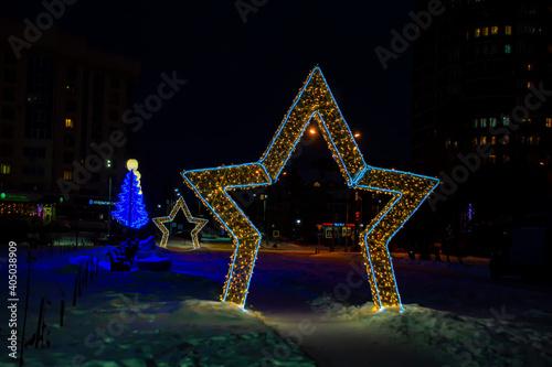New Year's installation in form of star at night in city. One in the foreground, the other in the back. View from the front.
